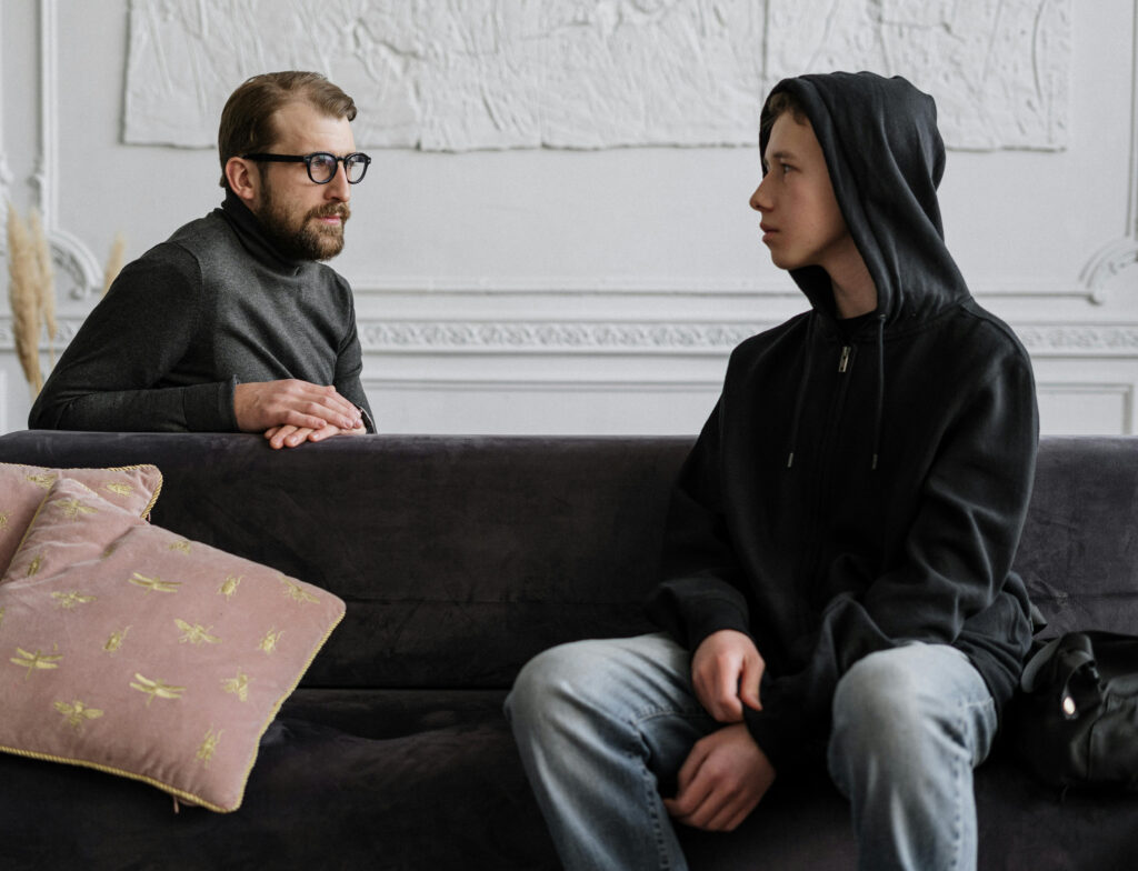 sad teen with father on sofa