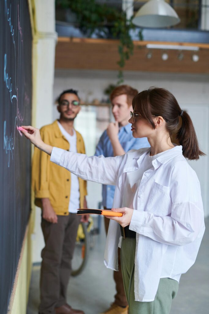 college students writing on a chalkboard