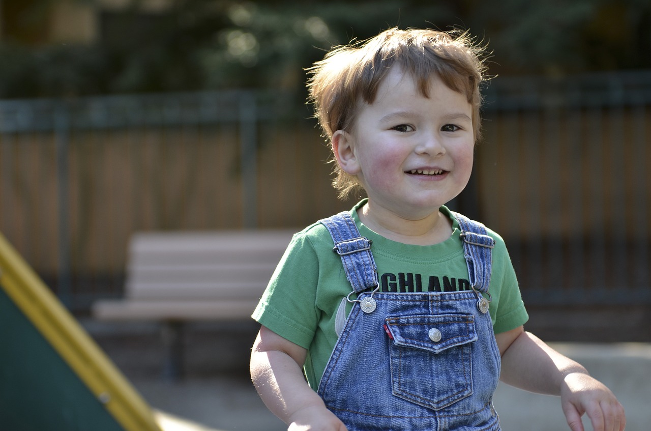 little boy smiling wearing overalls