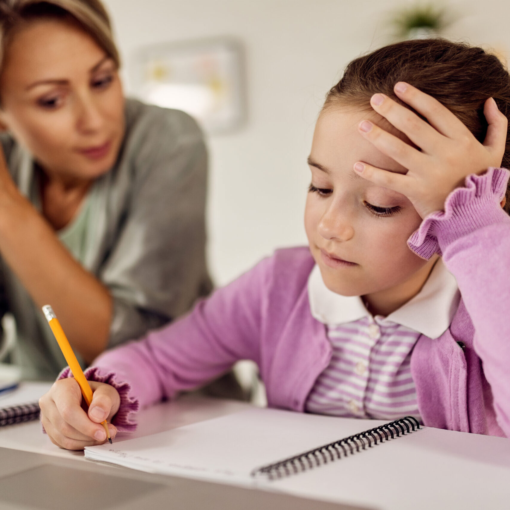 little-girl-writing-notebook-while-doing-homework-with-help-her-mother